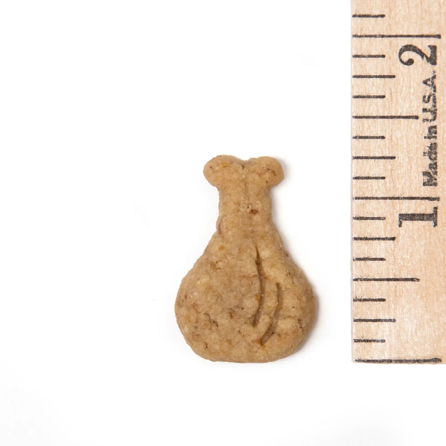 Small, natural dog treat shaped like a bag, shown next to ruler for scale on white background.